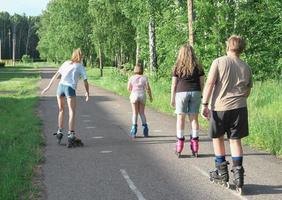 tieners rolschaatsen in de straat. vrienden samen op het platteland. Achteraanzicht van kinderen. vrije tijd en sport in de zomer. foto