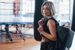 goed gezind. volwassen vrouw met zwarte tas en koptelefoon in de trainingsgymnastiek foto