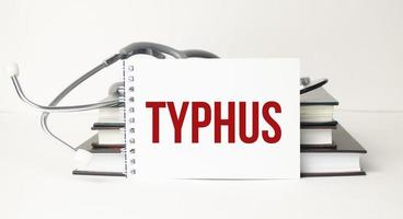 typhus woord op wit notitieboekje met stethoscoop foto