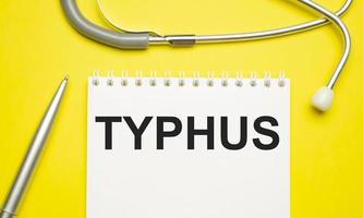 het woord typhus geschreven op een wit notitieblok op een gele achtergrond foto