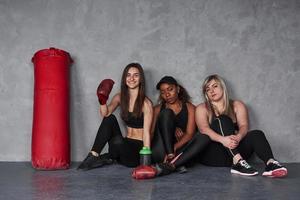 bij de rode duwbak. groep multi-etnische vrouwen die in de studio zitten tegen een grijze achtergrond foto