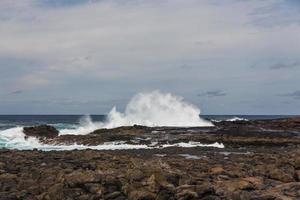 turbulente oceaangolven met wit schuim slaan kuststenen foto