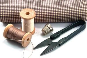 vingerhoed, naald, spoelen en schaar met doek voor het naaien op witte achtergrond foto
