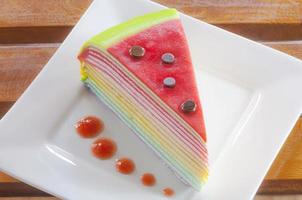 regenboog crêpe taart op een wit bord foto
