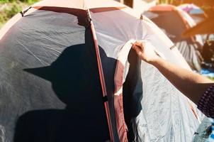 jonge man opent of sluit tentdeur in de ochtendzonlichttijd tijdens zijn kamperen in het lokale hooglandgebied chiang mai thailand - mensen campingconcept foto