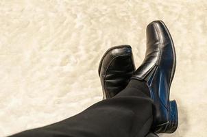 bovenaanzicht van oude zwarte broek en leren schoenen van ontspannen zittende zakenman op cementvloer. foto is gericht op schoenen.