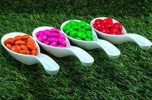kleurrijke chocoladesuikergoed geserveerd op lepels met groene grasachtergrond foto