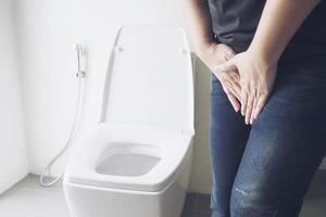 vrouw met hand in de buurt van toiletpot - gezondheidsprobleem concept foto