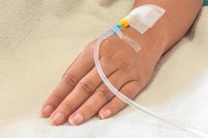 de hand van de patiënt met medicijndruppelinjectie, dame op een bed in een ziekenhuis foto
