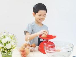 een jongen weegt rauwe eieren en bereidt zich voor om een cake te maken. foto