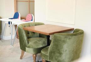 modern familiecafé interieur. een tafel met groene zacht gestoffeerde stoelen en kinderzitjes. plek voor familie dineren en tijd samen doorbrengen. elegante en comfortabele plek. foto