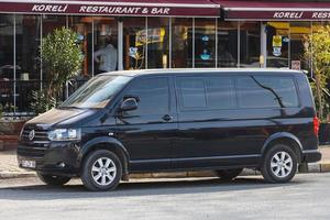 manavgat turkije 05 maart 2022 zwarte volkswagen transporter is geparkeerd op straat op een warme zomerdag tegen de bomen en het hek foto