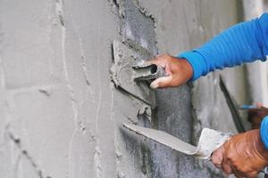 hand van arbeider die cement op muur pleistert foto