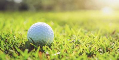 golfbal op groen gras met zonlicht foto