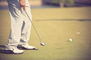 golfspeler bij de putting green die de bal in een hole.vintage color slaat foto