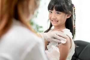 succesvolle covid-19-vaccinatie. schattig klein meisje terwijl ze wordt ingeënt tegen het coronavirus foto