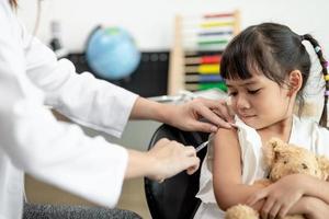 succesvolle covid-19-vaccinatie. schattig klein meisje terwijl ze wordt ingeënt tegen het coronavirus foto