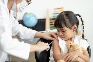 succesvolle covid-19-vaccinatie. schattig klein meisje terwijl ze wordt ingeënt tegen het coronavirus foto