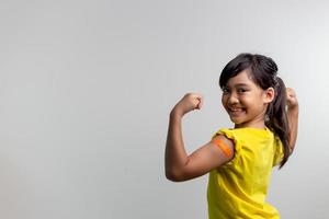 covid 19 vaccins voor kinderen concept. studio een portret van een schattig Aziatisch meisje na het krijgen van zijn eerste dosis vaccin. immuun, veilig, beschikbaar, terug naar school. foto