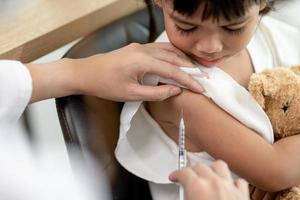 succesvolle covid-19-vaccinatie. schattig klein meisje terwijl ze wordt ingeënt tegen het coronavirus foto