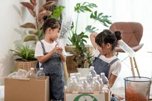 lachende kinderen die plezier hebben terwijl ze plastic flessen en papier scheiden in een prullenbak foto