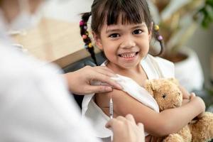 succesvolle covid-19-vaccinatie. schattig klein meisje terwijl ze wordt ingeënt tegen het coronavirus foto