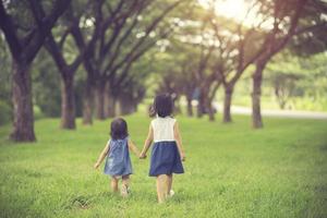 twee kleine zusjes die elkaars hand vasthouden en vooruit rennen. vintage kleur foto
