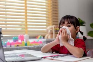 ongezond kind dat zijn neus in een tissue blaast, kind dat lijdt aan een loopneus of niest, een meisje verkouden wordt als het seizoen verandert, kinderneus veegt met tissues foto