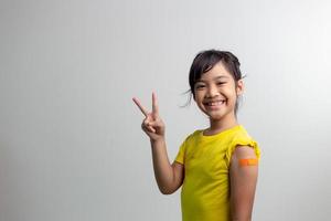 covid 19 vaccins voor kinderen concept. studio een portret van een schattig Aziatisch meisje na het krijgen van zijn eerste dosis vaccin. immuun, veilig, beschikbaar, terug naar school. foto