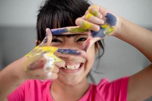 onderwijs, school, kunst en schildersconcept - klein studentenmeisje dat geschilderde handen toont foto