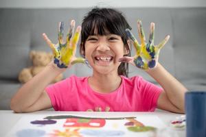 onderwijs, school, kunst en schildersconcept - klein studentenmeisje dat geschilderde handen toont foto