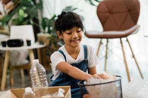 lachende kinderen die plezier hebben terwijl ze plastic flessen en papier scheiden in een prullenbak foto