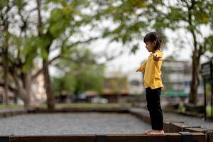 Aziatisch kindmeisje dat op de speelplaats in het openluchtpark speelt. Gelukkig moment en goede emotie foto