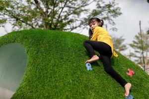 kind spelen op buitenspeeltuin. kinderen spelen op school of kleuterschool. actieve jongen op kleurrijke glijbaan en schommel. gezonde zomeractiviteit voor kinderen. klein meisje buitenshuis klimmen. foto