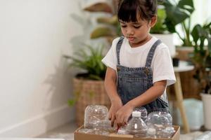 lachende kinderen die plezier hebben terwijl ze plastic flessen en papier scheiden in een prullenbak foto