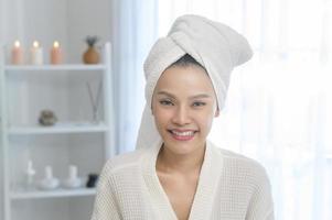 portret van een jonge glimlachende aziatische mooie vrouw die een witte badjas draagt na het douchen? foto