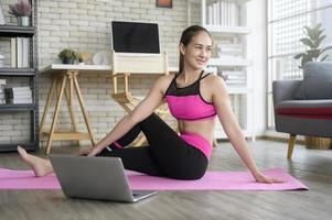 fit jonge vrouw die thuis yoga beoefent via online les met professionele instructeur, sport en gezond levensstijlconcept. foto