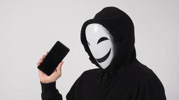 anonieme hacker en gezichtsmasker met smartphone in de hand. foto