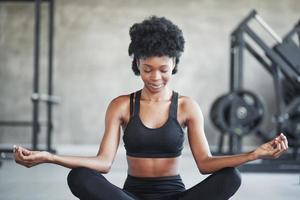 rustige geest. Afro-Amerikaanse vrouw met krullend haar en in sportieve kleding heeft een fitnessdag in de sportschool foto