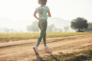 jonge dame geniet van een gezonde levensstijl tijdens het joggen langs een landweg foto