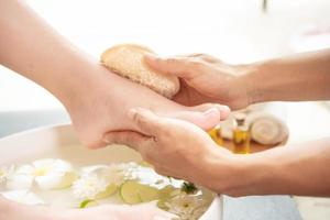 voeten wassen in de spa voor de behandeling. spa-behandeling en product voor vrouwelijke voeten en hand spa. witte bloemen in keramische kom met water voor aromatherapie in de spa. foto