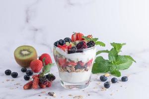 zelfgemaakte muesli, kom haver muesli met yoghurt, verse bosbessen, moerbei, aardbeien, kiwi, munt en noten bord voor gezond ontbijt, kopieer ruimte. gezond ontbijtconcept. schoon eten. foto