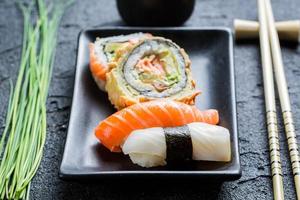 close-up van verse sushi, donkere keramiek en eetstokje