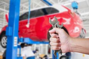 automonteur met moersleutel bij de autoreparatiegarage foto