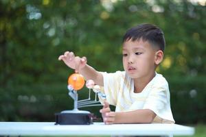 Aziatische jongen die speelgoed in het zonnestelsel leeft, thuisleerapparatuur, tijdens nieuwe normale verandering na coronavirus of pandemische situatie na covid-19-uitbraak foto