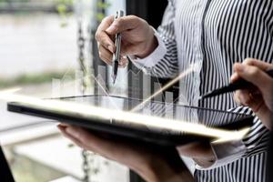 twee zakenmensen die een tablet gebruiken om financiële bedrijfsrapporten te bekijken, afbeeldingen met financiële en numerieke groeigegevens. het concept van financieel beheer om te groeien en winstgevend te zijn. foto