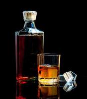 fles en glas whisky met ijs foto