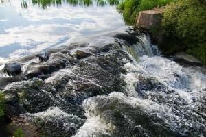 een kleine rivierwaterval op een heldere zonnige zomerdag. foto