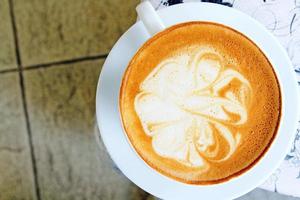 bovenaanzicht van kopje kunst cappuccino of latte koffie op witte achtergrond of tafel in café winkel. plat leggen van warm drinken in glas met kopieerruimte. voedsel ontwerpconcept. foto