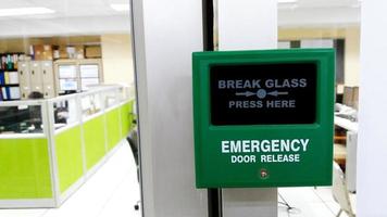 close-up groene nooddeurontgrendeling om te ontsnappen uit de binnenkamer met een wazige kantoorachtergrond foto